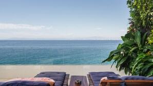Zona relax in spiaggia con lettini e tavolino, vista mare.