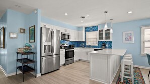 A modern kitchen with stainless steel appliances, a central island, and light blue walls.