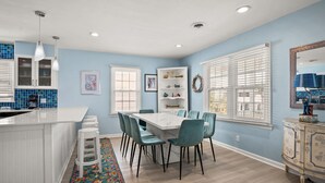 A kitchen with a white island, blue chairs, and a dining table.