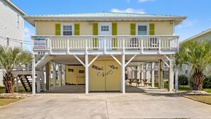 A two-story building with a balcony, a signboard, and a door with artwork.