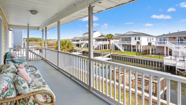 A covered porch with a view of a marina and row houses.