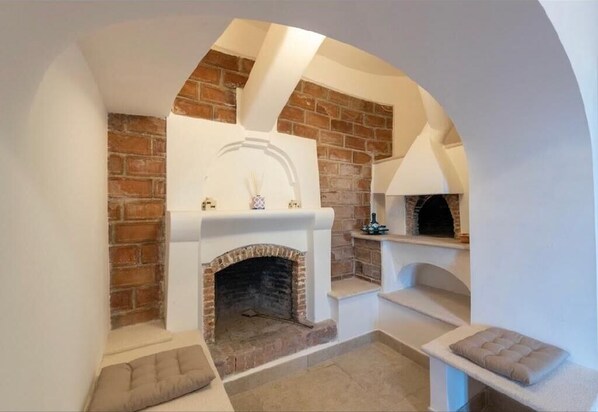 Cozy room with a fireplace, curved archway, and two seating areas for relaxation.