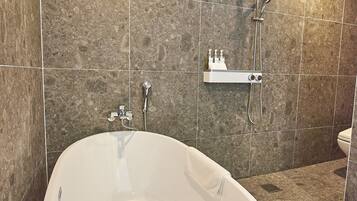 A modern bathroom with a freestanding bathtub, a showerhead, and a toilet.