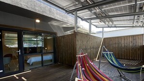 A modern room with a glass door leading to a balcony, a hammock, and a wooden floor. - Bonathree Hotel (Busan)