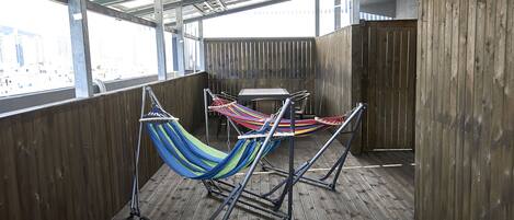 A hammock set up on a wooden deck with a view of the city.