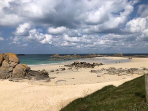 A beach with large rocks, a sandy shore, and a cloudy sky. - Le Petit Pingouin, sleeps 6, sea and beach 300 metres away (Cléder)