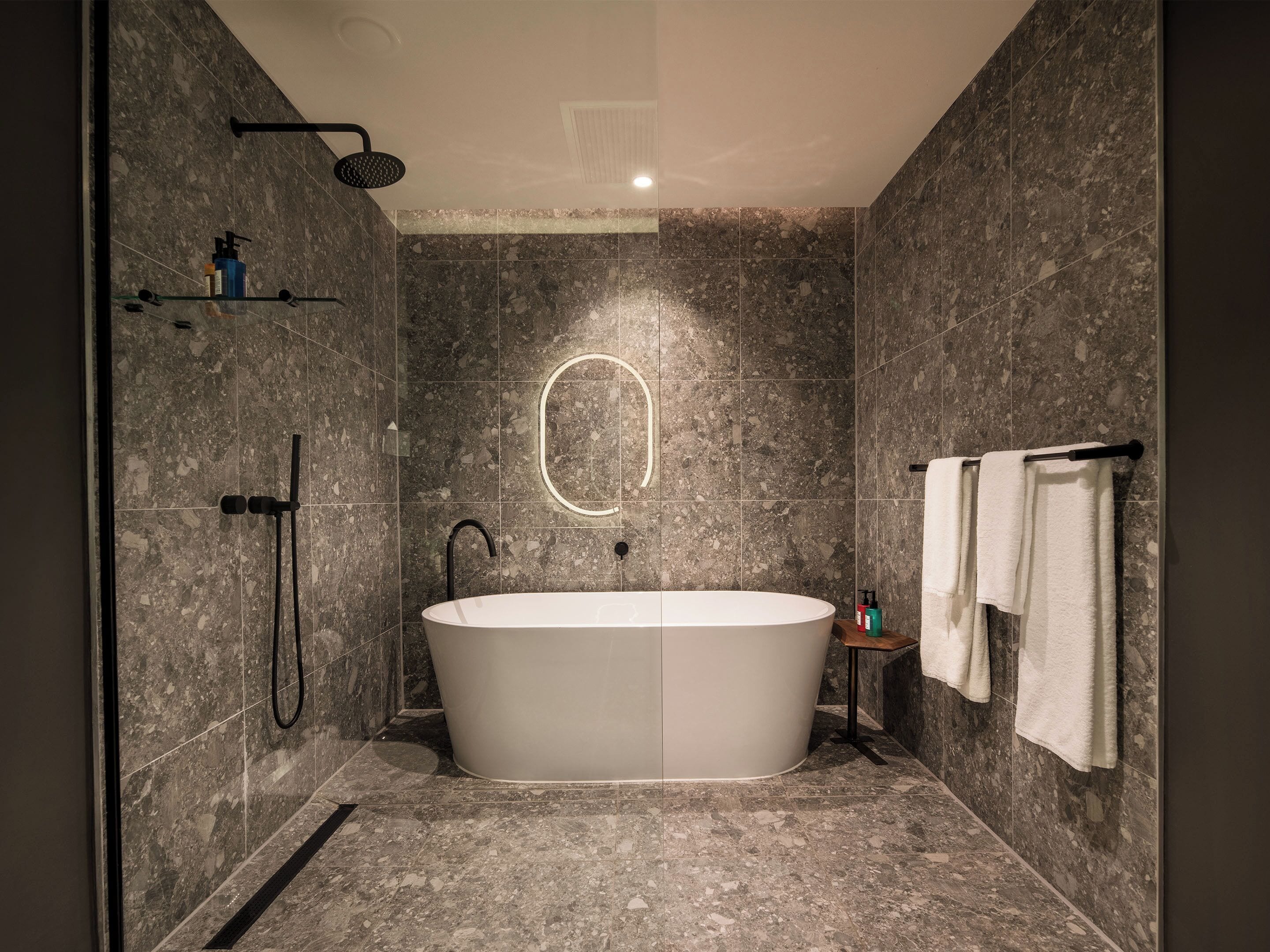 A modern bathroom with a freestanding bathtub, a showerhead, and a towel rack.