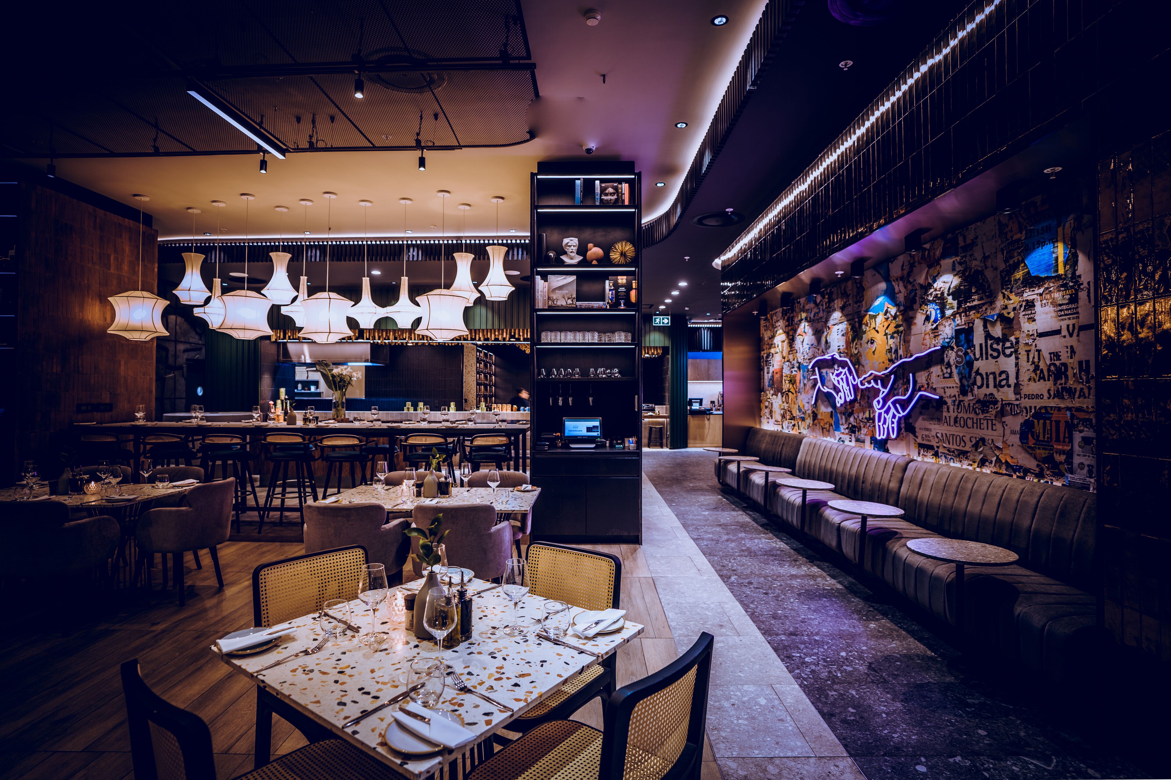 A modern restaurant with a bar area, seating, and a neon-lit wall.