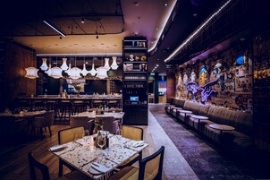 A modern restaurant with a bar area, seating, and a neon-lit wall.
