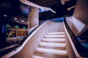 A modern interior with a curved staircase, a bar area, and a seating section.