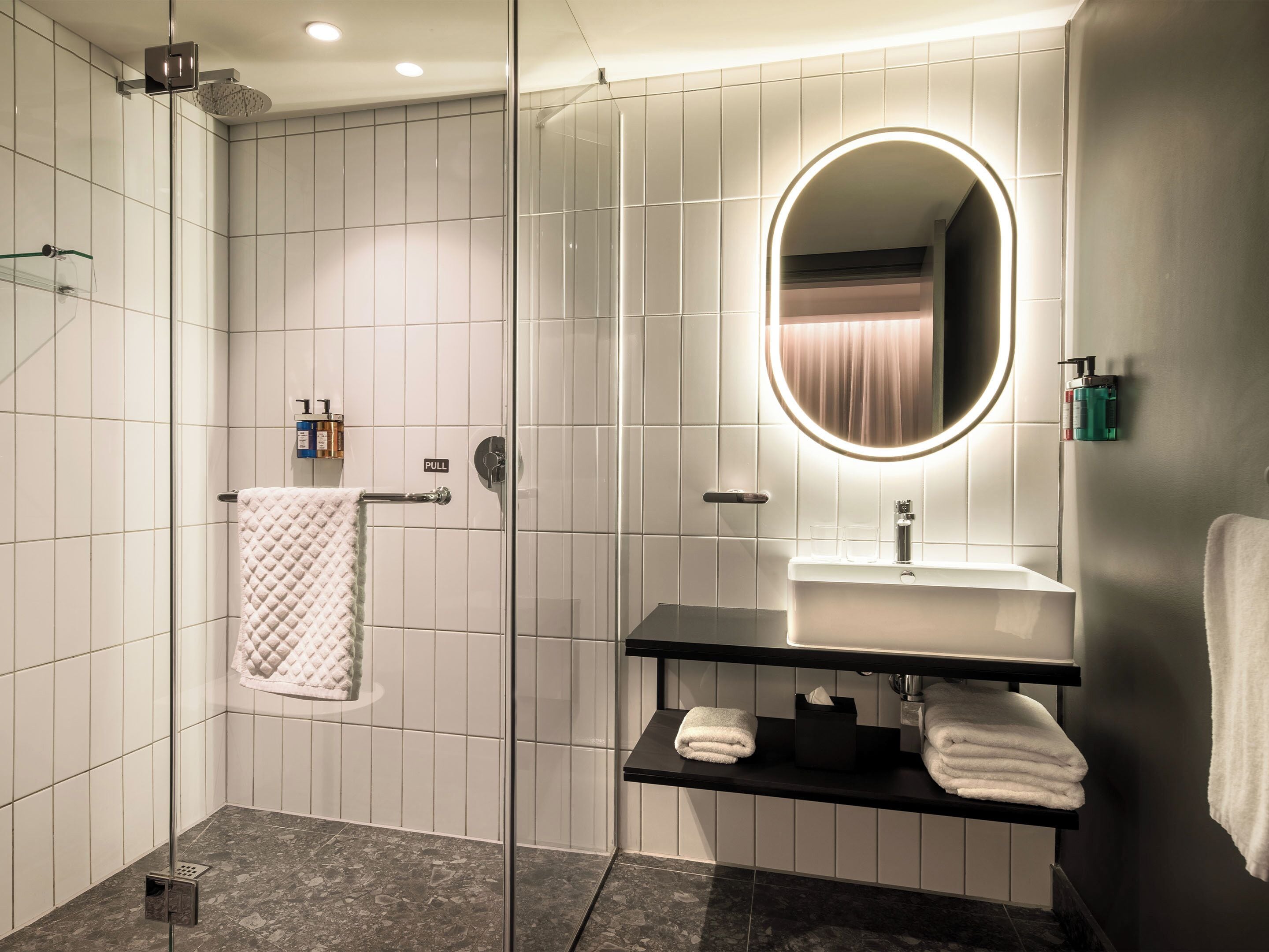 A modern bathroom with a glass-enclosed shower, a vanity with a mirror, and a towel rack.