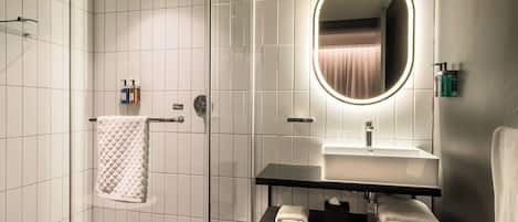 A modern bathroom with a glass-enclosed shower, a vanity with a mirror, and a towel rack.