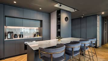 A modern kitchen with a marble countertop, built-in appliances, and a bar area with velvet barstools.
