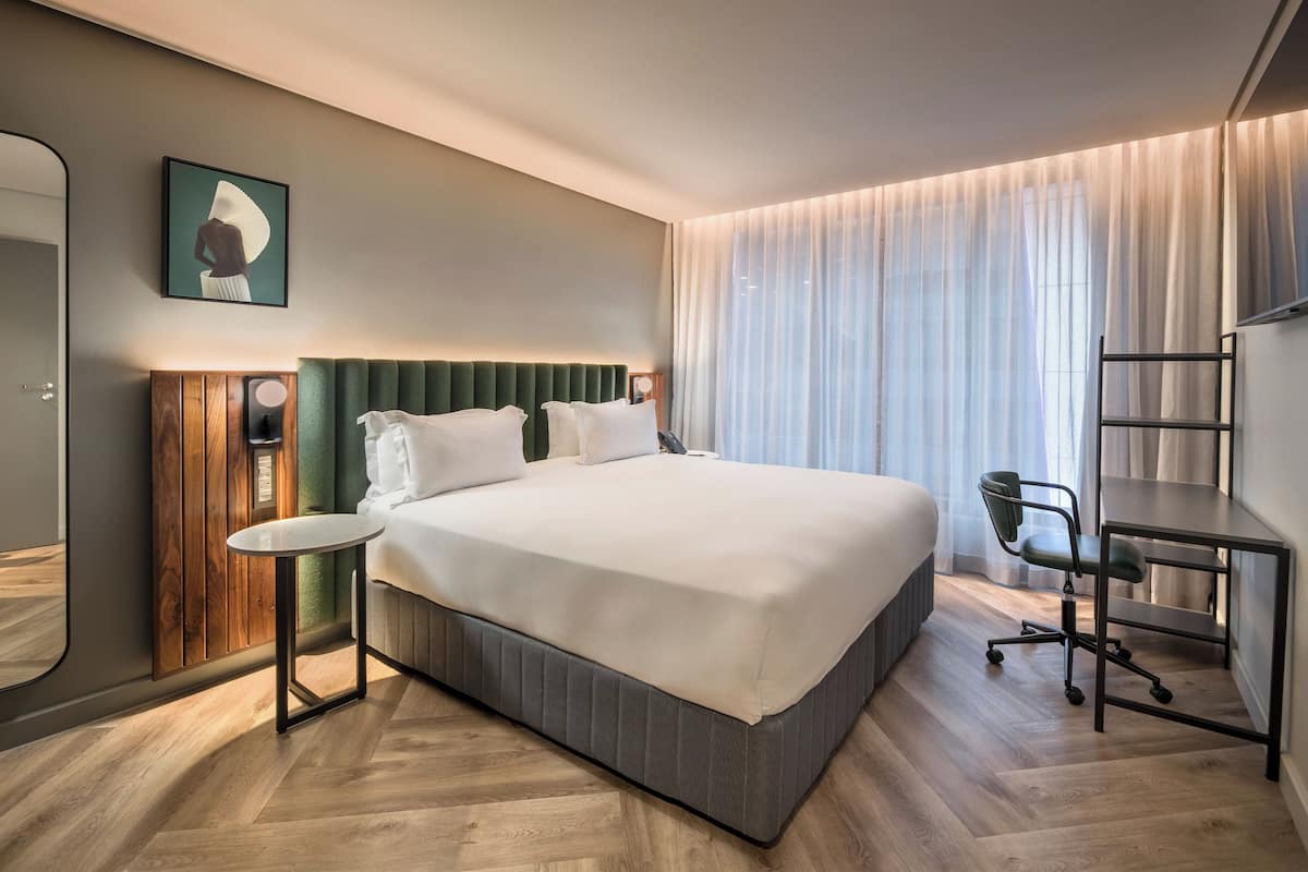 Ein modernes Hotelzimmer mit einem großen Bett, einem Schreibtisch und einem Sessel.