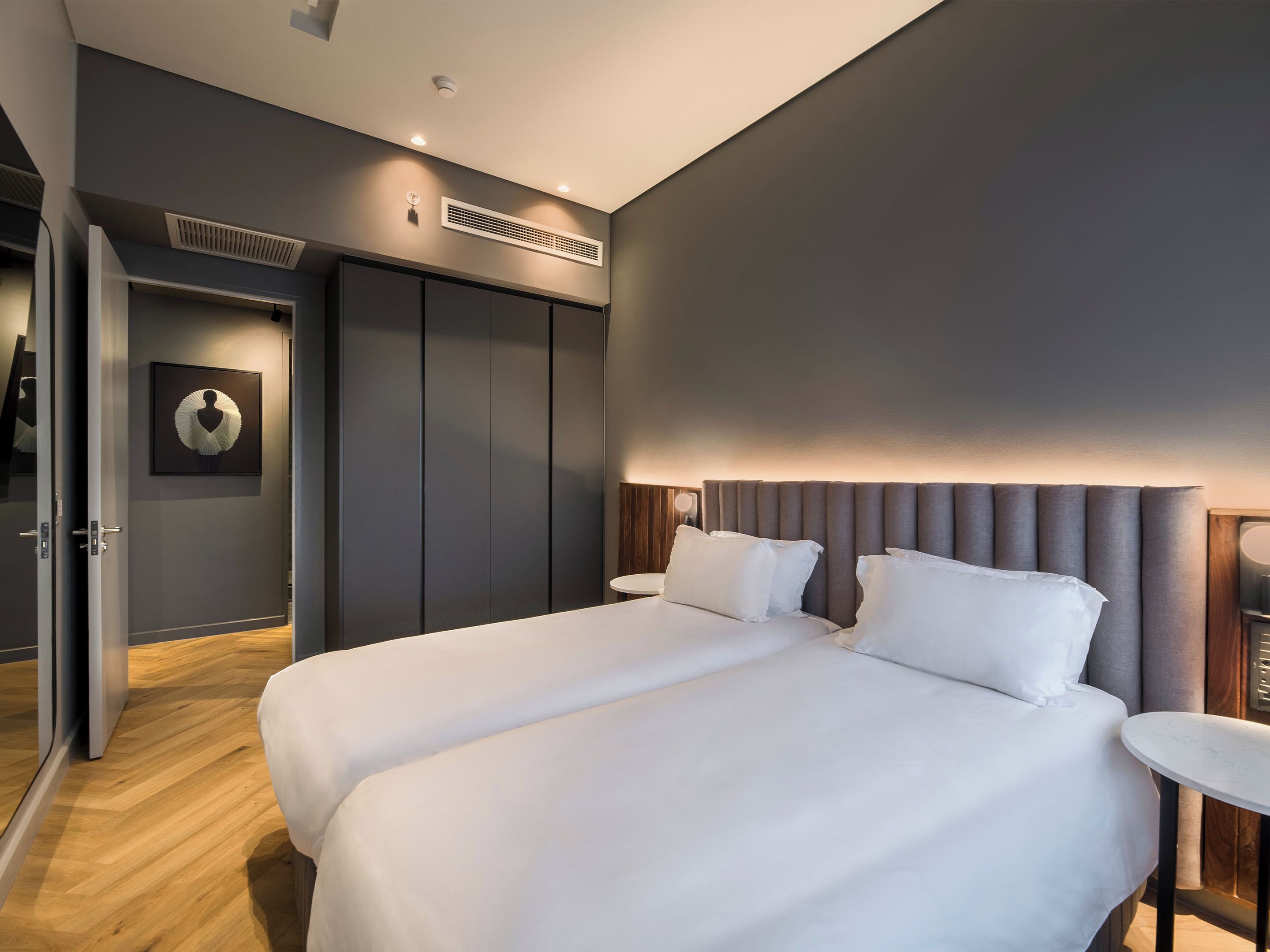 A modern hotel room with a large bed, a bedside table, and a wardrobe.