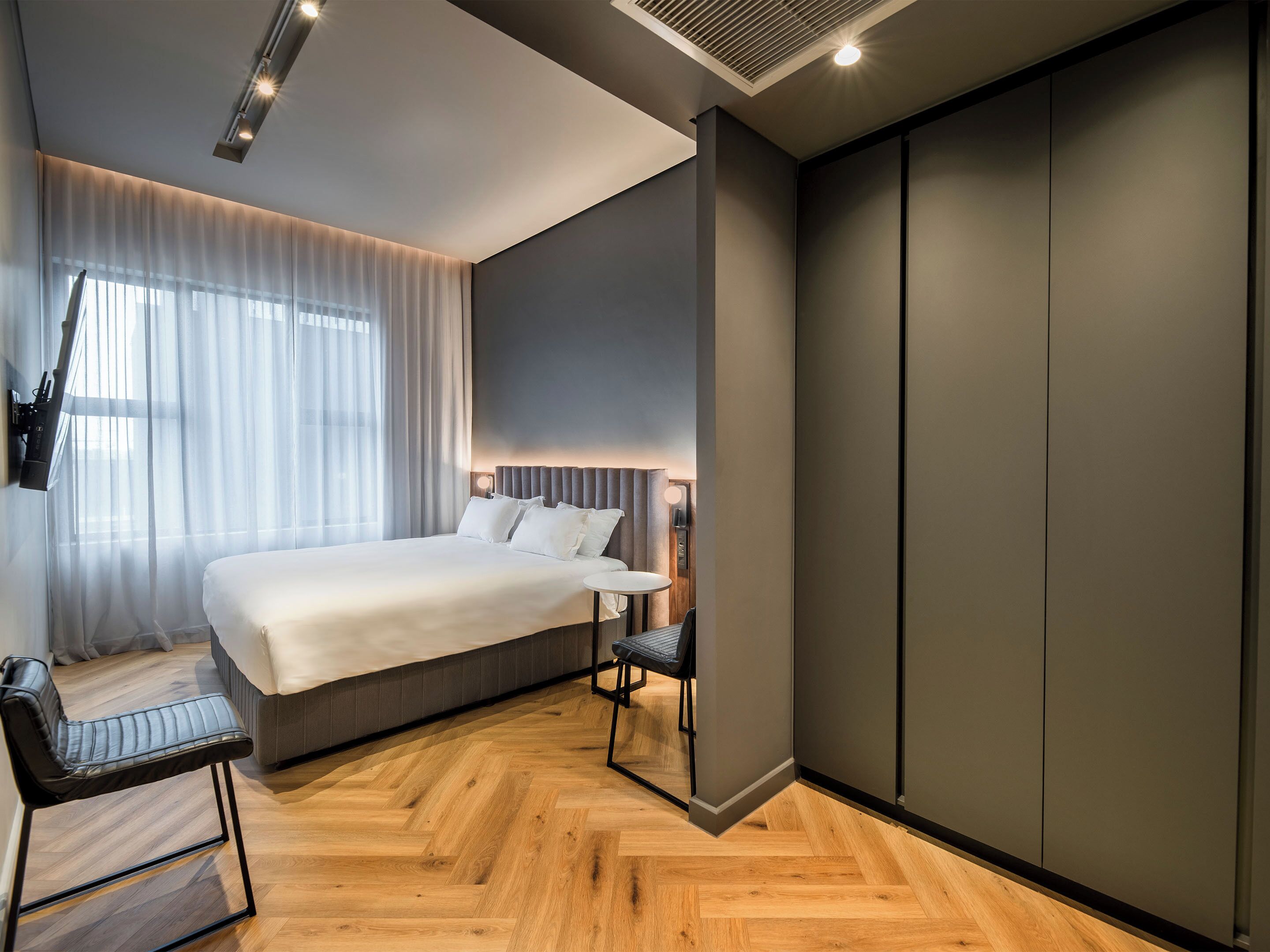 Une chambre d’hôtel moderne, dotée d’un grand lit, d’un bureau et d’une chaise.