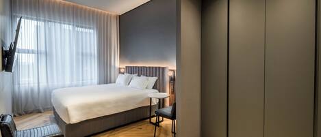 Une chambre d’hôtel moderne, dotée d’un grand lit, d’un bureau et d’une chaise.