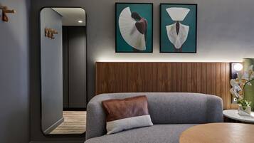 Ein modernes Wohnzimmer mit einem grauen Sofa, einem Holznachttisch und zwei gerahmten Kunstwerken an der Wand.