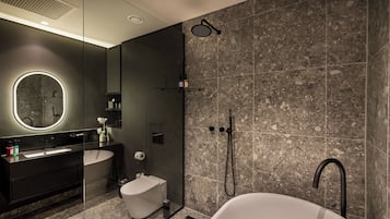 Un baño moderno con una bañera independiente, una ducha con cerramiento de vidrio y un tocador con un espejo grande.