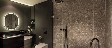 A modern bathroom with a freestanding bathtub, a glass-enclosed shower, and a vanity with a large mirror.