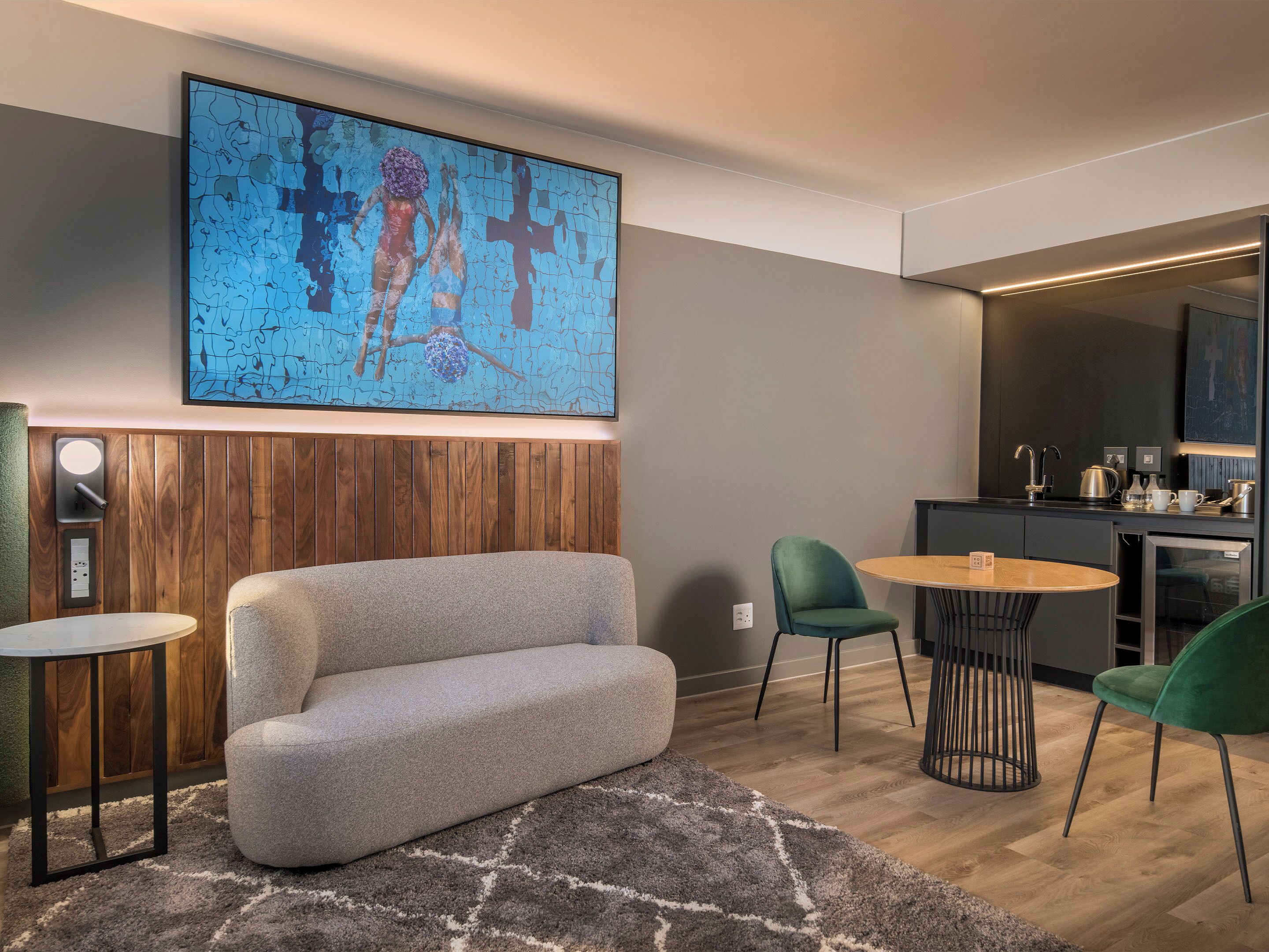 Una sala de estar moderna con un sofá, una mesa redonda y dos sillas. Un cuadro abstracto de gran tamaño cuelga de la pared.
