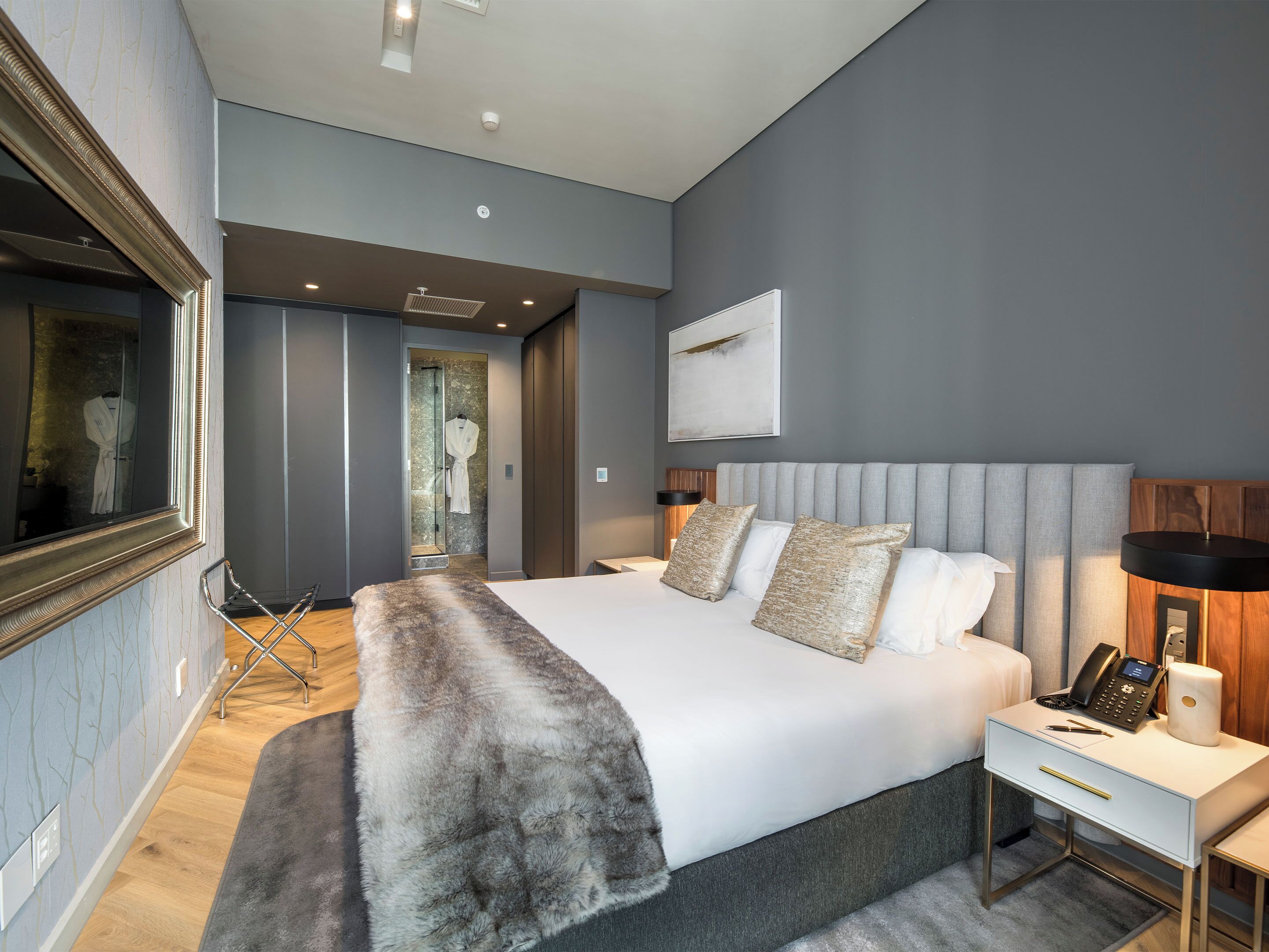 Ein modernes Schlafzimmer mit einem großen Bett, Nachttischen, einem Spiegel und einer Duschkabine.