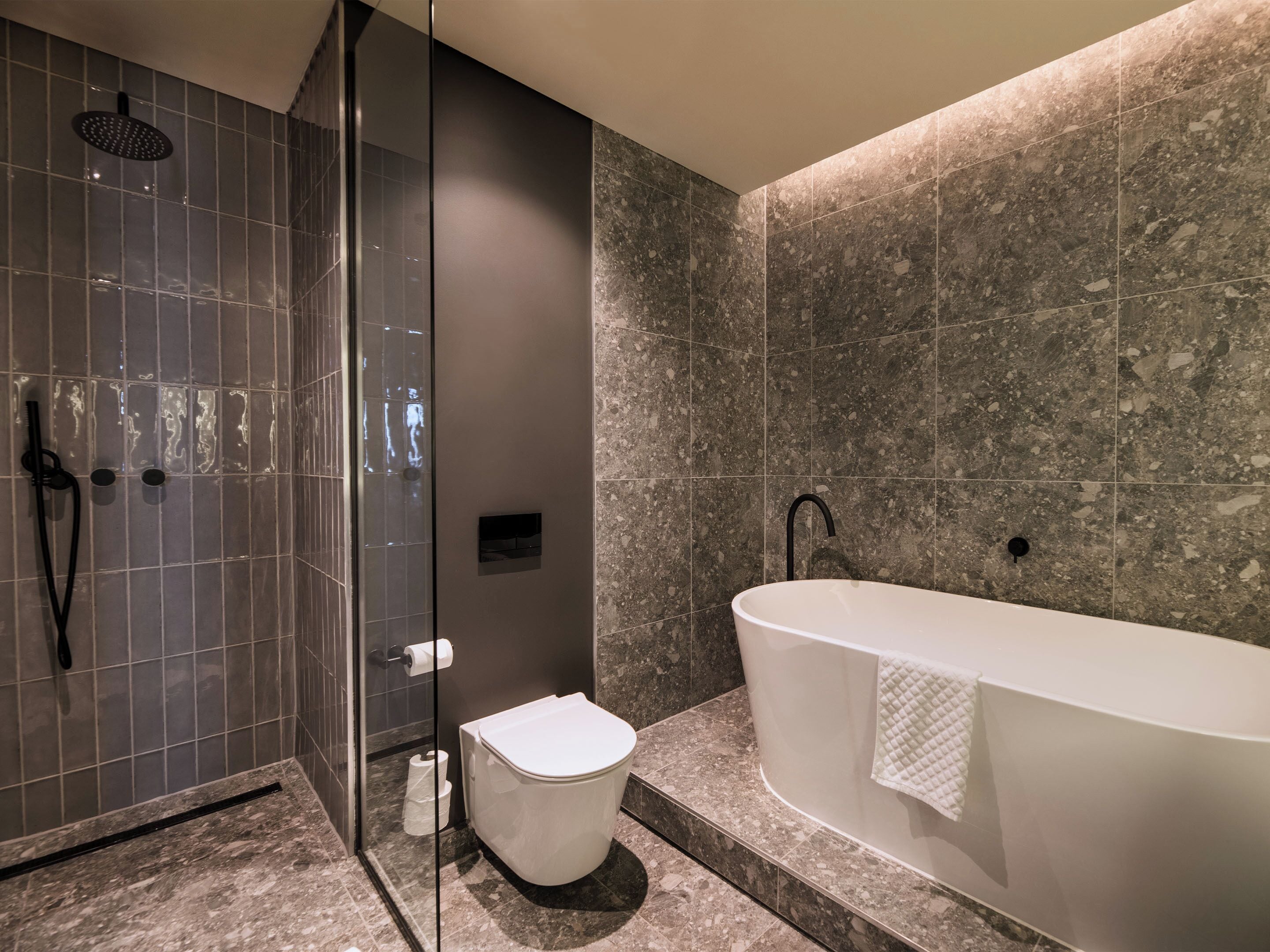 Un baño moderno con una bañera independiente, una ducha con mampara de vidrio y un inodoro.