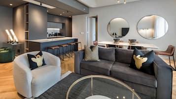 Una sala de estar moderna con un sofá gris, una mesa de centro redonda y una zona de comedor con una mesa y sillas blancas.