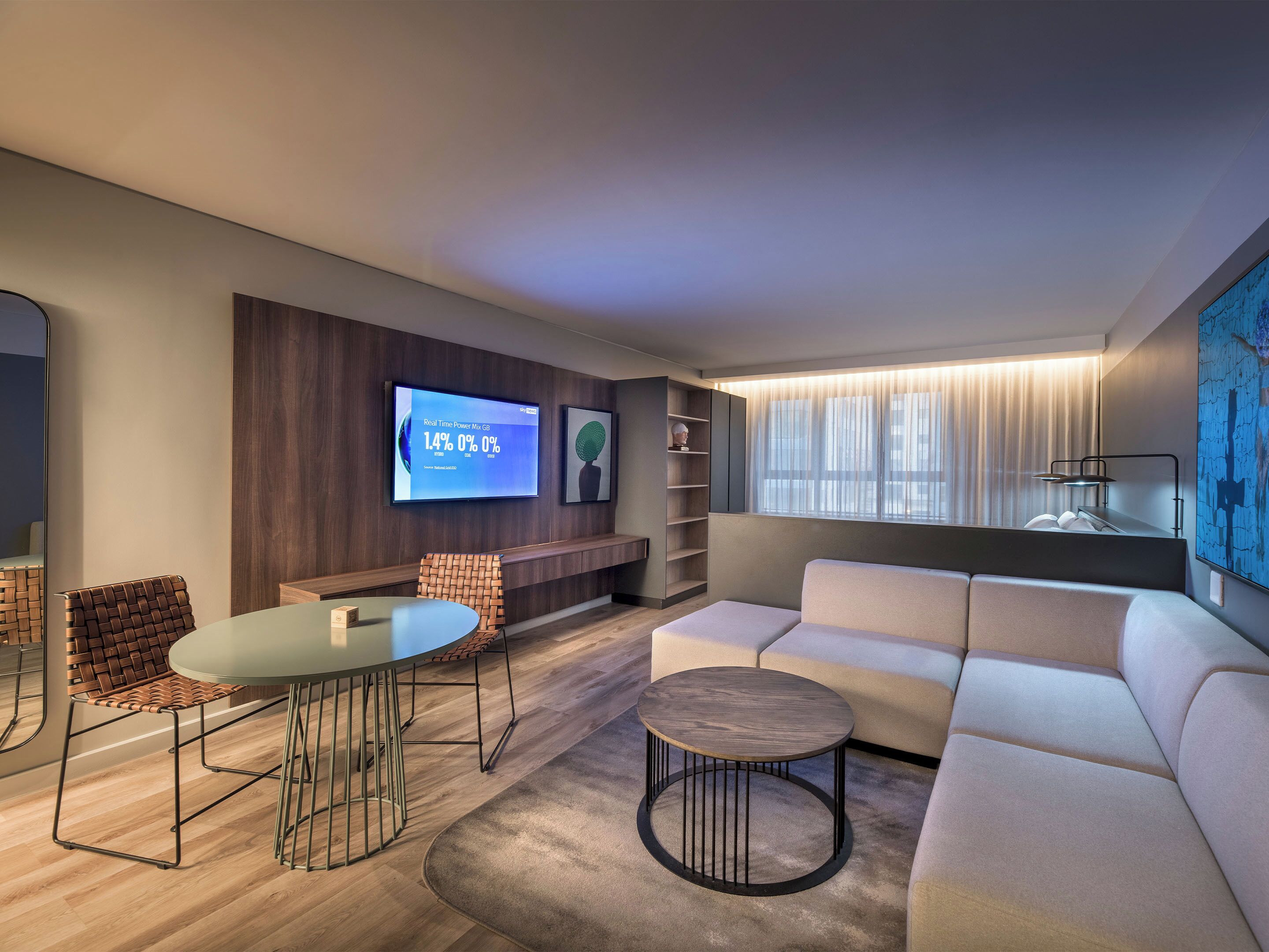 A modern living room with a flat-screen TV, a sofa, a coffee table, and a dining area with a chair and table.