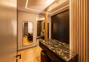 A modern bathroom with a marble countertop, wooden paneling, and a large mirror.