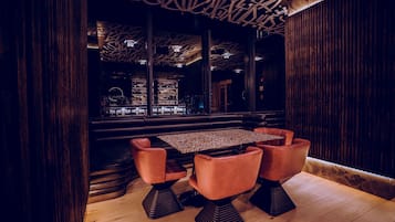 A modern interior with a wooden floor, a central table with four chairs, and a patterned ceiling.