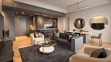 A modern living room with a sofa, armchairs, a coffee table, and a dining area with a TV and circular mirrors.