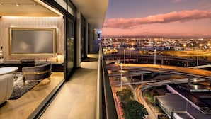 A modern hotel room with a large window, a sofa, and a flat-screen TV.