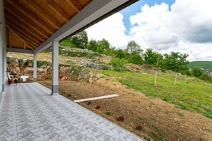 Relax on the patio overlooking a serene garden with a hill in the background.