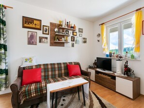 Relax in this inviting living room with a sofa, TV, and decorative shelf.