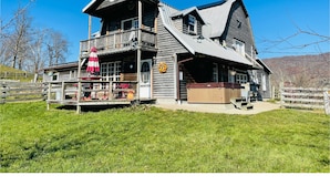 A wooden cabin with a balcony, a covered porch, and a hot tub. - Loft apartment on Farm with Hot Tub, pond and total privacy.  (Harman)