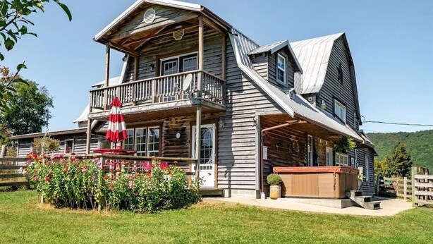 A two-story log cabin with a balcony, a hot tub, and a well-maintained garden. - Loft apartment on Farm with Hot Tub, pond and total privacy.  (Harman)