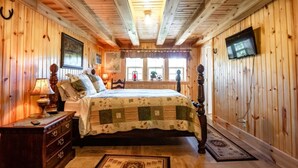 A cozy wooden cabin bedroom with a bed, dresser, and a television mounted on the wall. - Loft apartment on Farm with Hot Tub, pond and total privacy.  (Harman)
