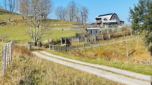 A rural setting with a house on a hill, surrounded by a wooden fence and a dirt path leading to it. - Loft apartment on Farm with Hot Tub, pond and total privacy.  (Harman)
