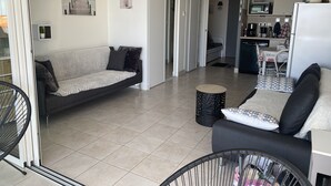 A modern living room with a sofa, a small round table, and a baby crib.