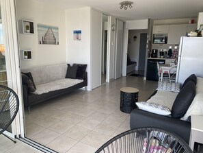 A modern living room with a sofa, a small round table, and a baby crib. - SEAFRONT APARTMENT COTE SAUVAGE (Les Sables-d'Olonne)