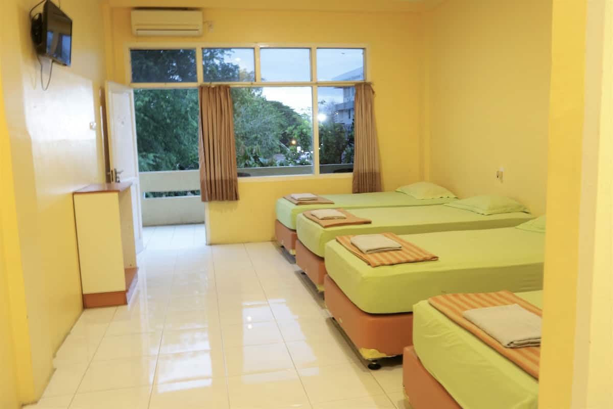 A hotel room with three beds, a desk, and a window with curtains.