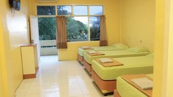 A hotel room with three beds, a desk, and a window with curtains.