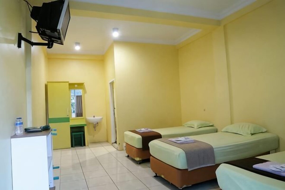 A room with two beds, a sink, a mirror, and a television.