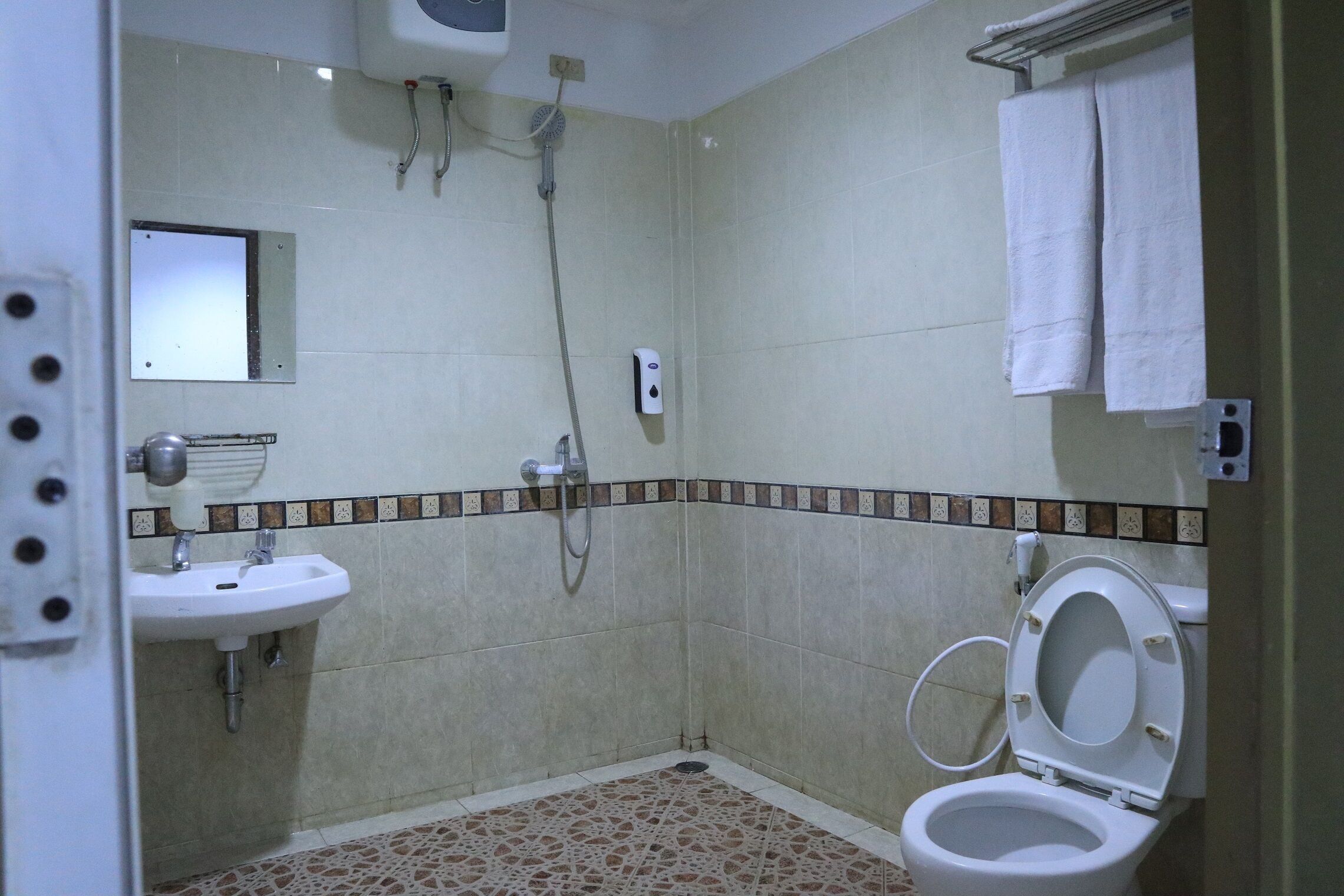 Un bagno con lavandino, WC, doccia e pavimento piastrellato.