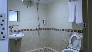Un bagno con lavandino, WC, doccia e pavimento piastrellato.