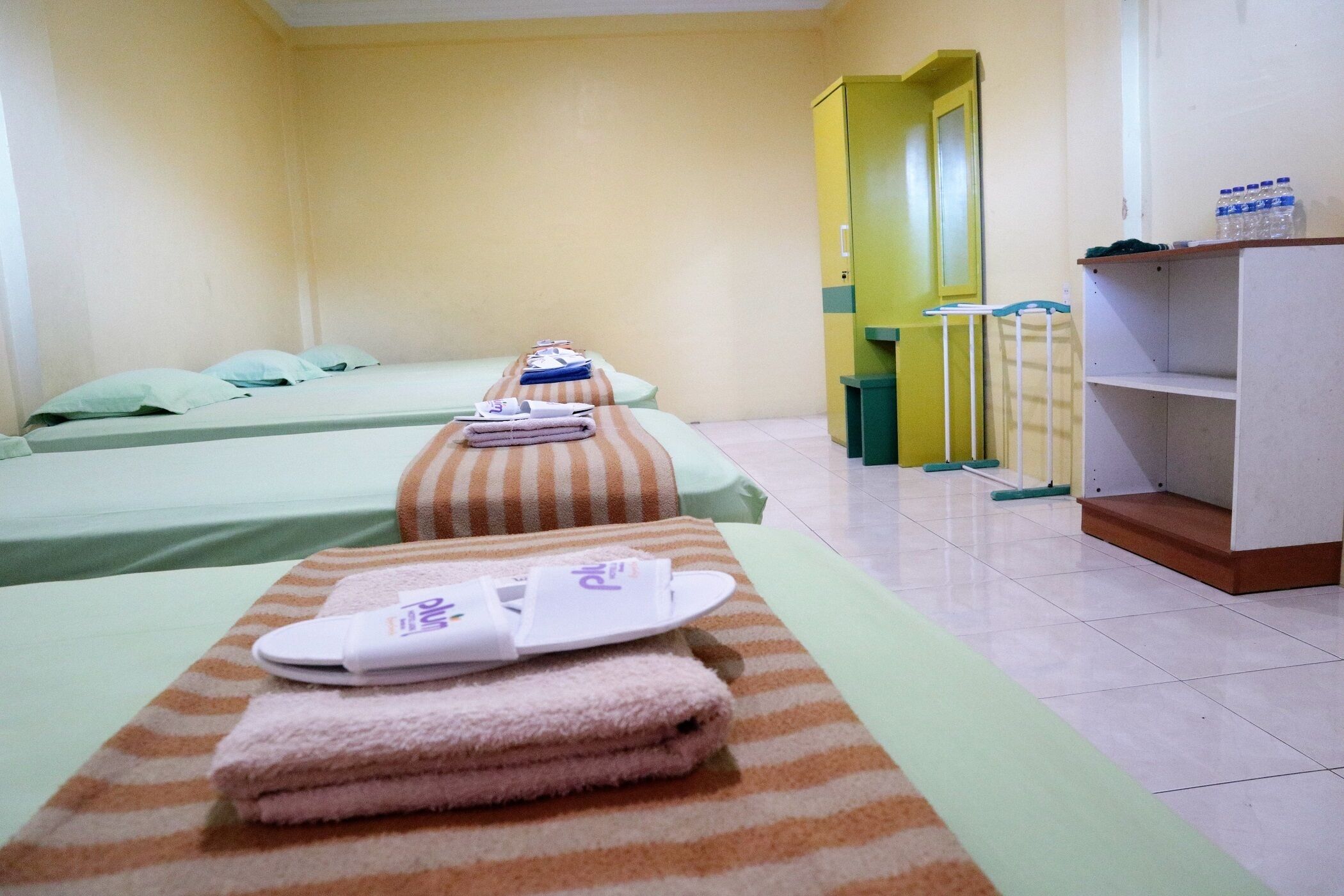 A hotel room with two beds, a bathroom, and a small kitchenette.