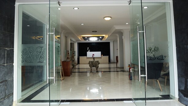 Un vestíbulo de hotel con un panel de vidrio, una recepción y una zona de estar.