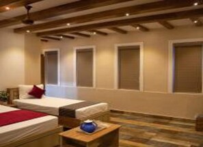 A hotel room with two beds, a wooden ceiling, and a small table with a vase. - Hotel Ganesh Palace (Rameshwaram)
