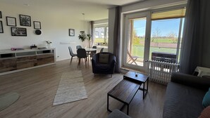 Ein geräumiges Wohnzimmer mit Sofa, Couchtisch und Essbereich mit Stühlen.